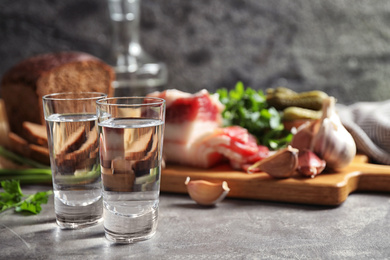 Photo of Cold Russian vodka with snacks on grey table, closeup