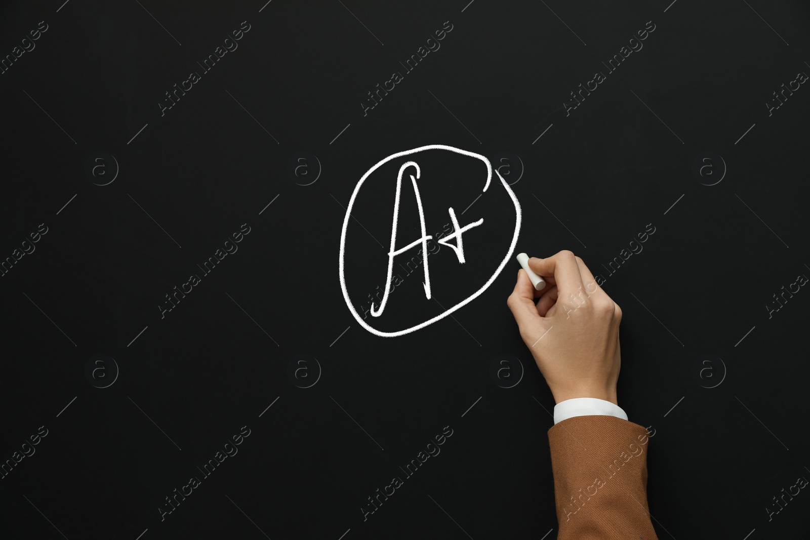 Image of School grade. Teacher encircling letter A and plus symbol with chalk on blackboard