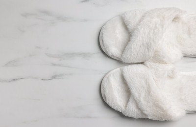 Photo of Pair of soft slippers on white marble floor, top view. Space for text