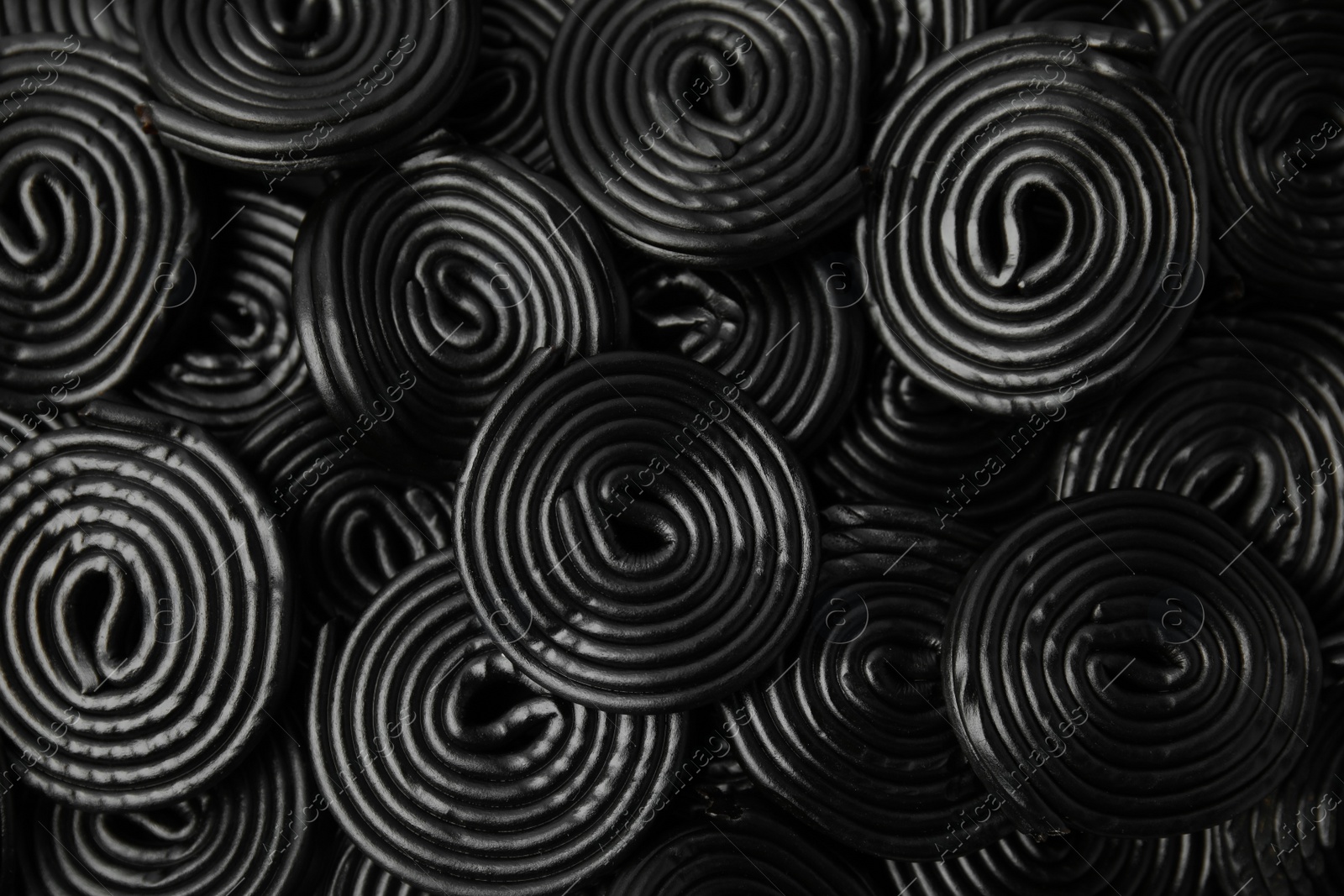 Photo of Tasty black liquorice candies as background, top view