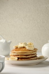 Photo of Delicious pancakes with bananas, honey and butter on white wooden table. Space for text