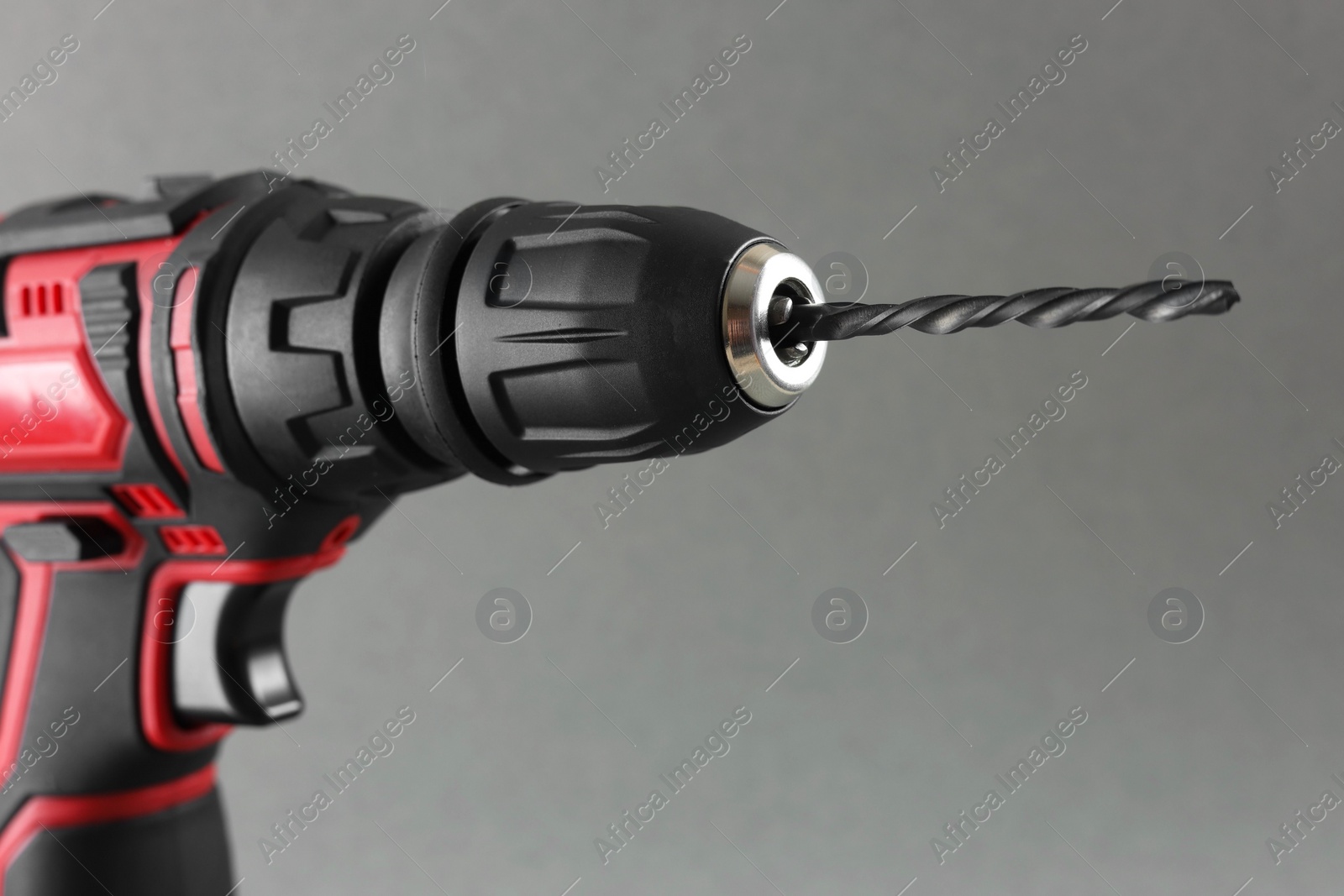 Photo of Modern electric screwdriver on grey background, closeup