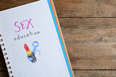 Notebook with phrase "SEX EDUCATION" on wooden background, top view. Space for text