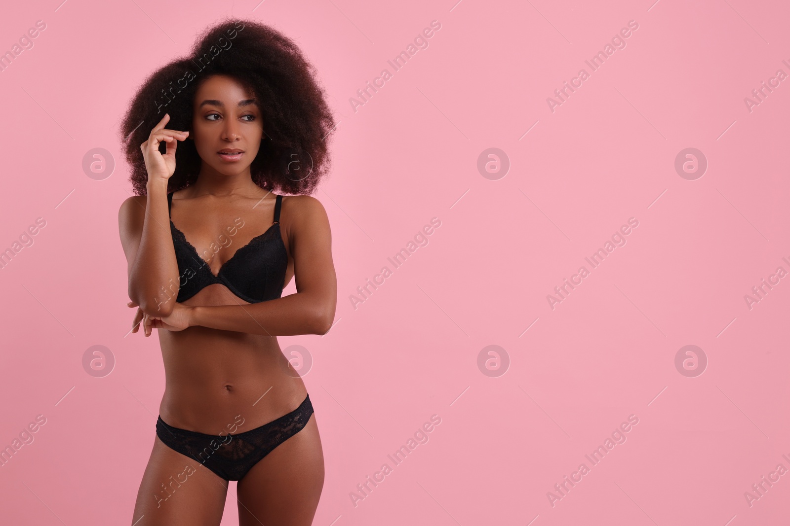 Photo of Beautiful woman in elegant black underwear on pink background, space for text