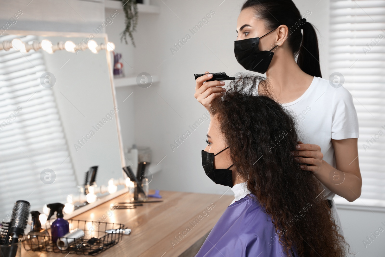 Photo of Professional stylist working with client in salon. Hairdressing services during Coronavirus quarantine