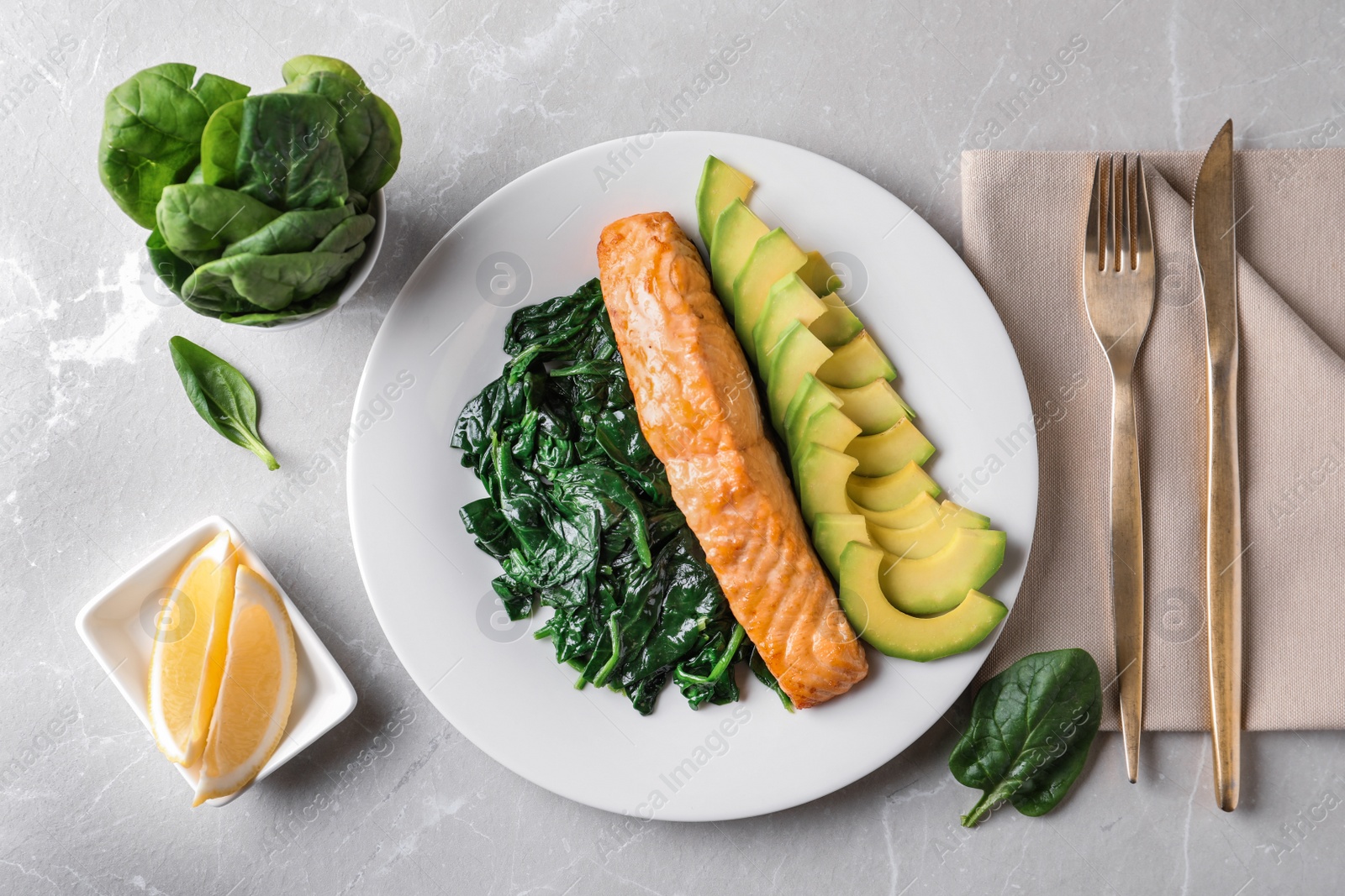 Photo of Tasty salmon with spinach and avocado on marble table, flat lay