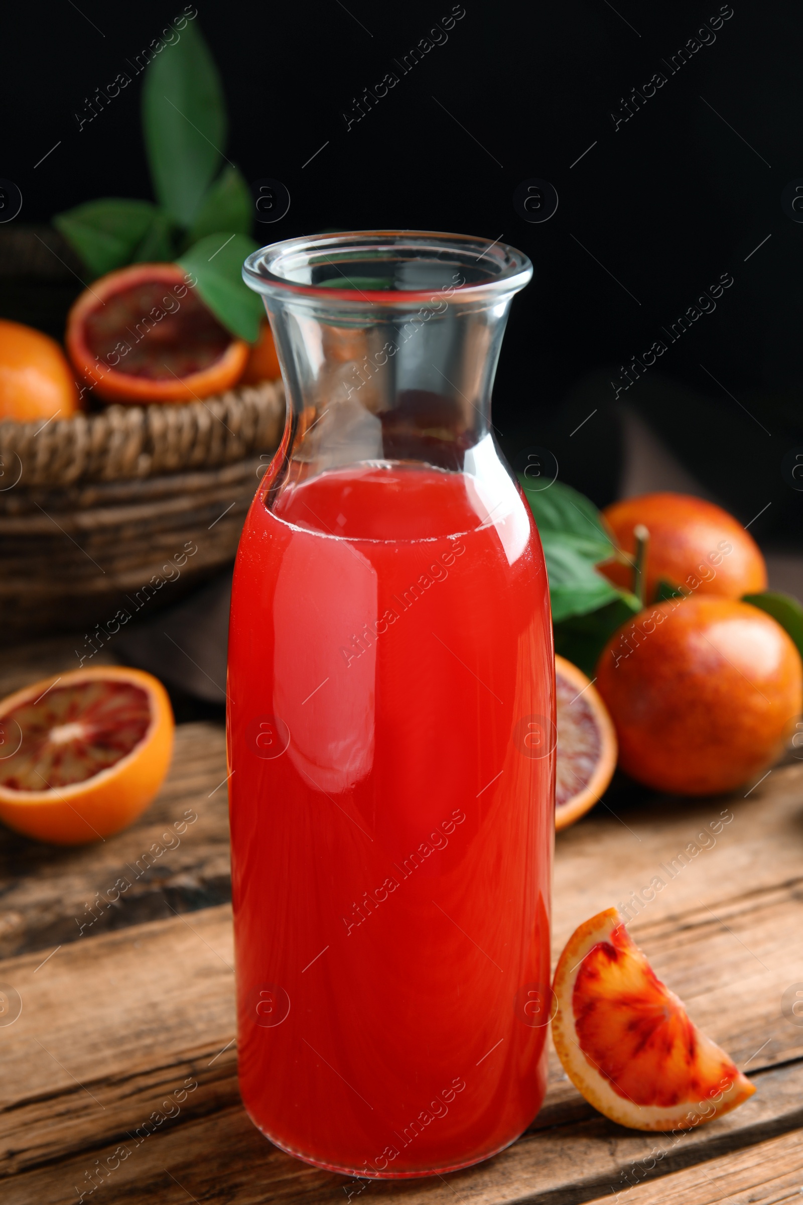 Photo of Tasty sicilian orange juice in glass bottle and fruits on wooden table