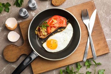 Fried sunny side up egg with sandwich in pan served on table, flat lay