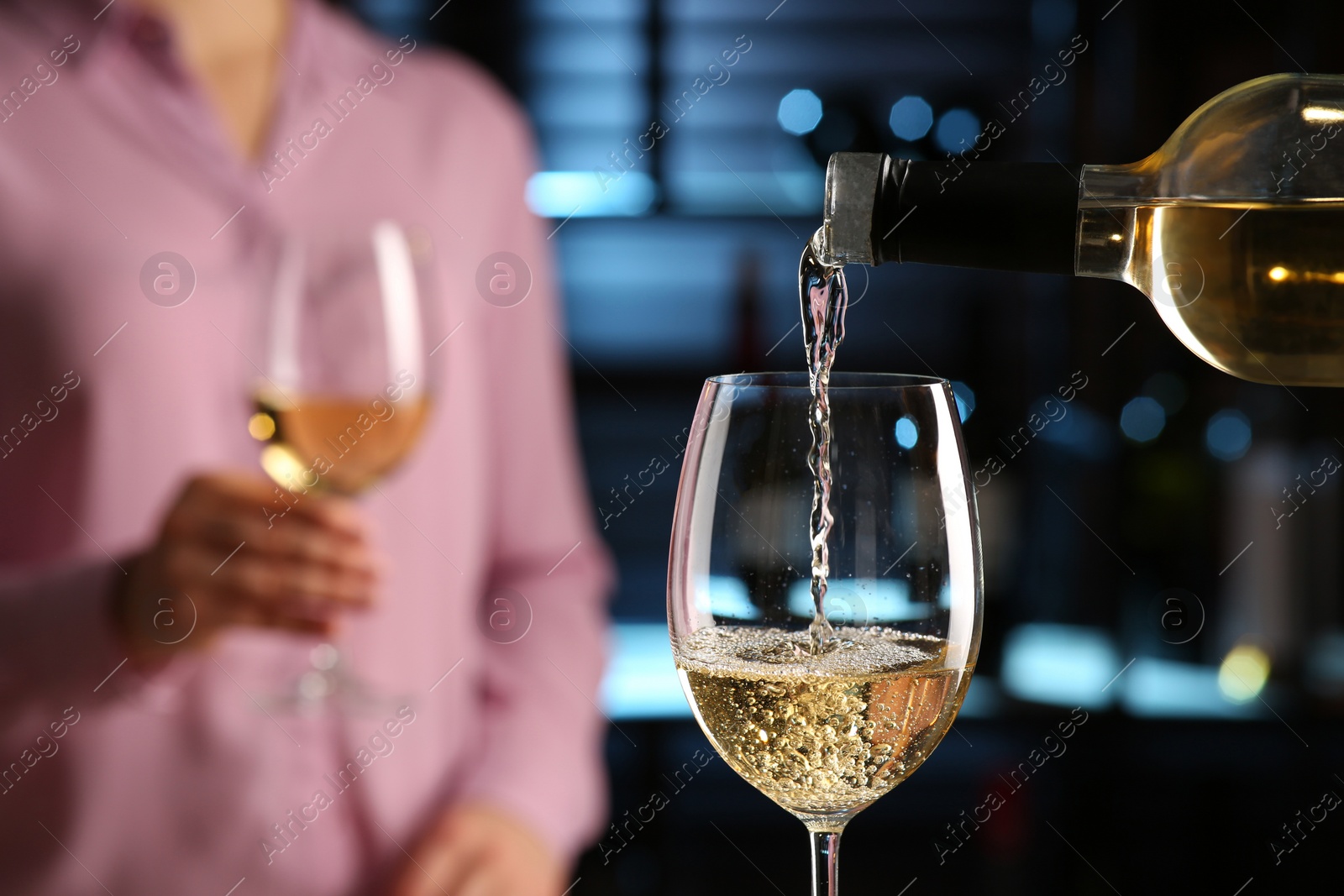 Photo of Pouring white wine from bottle into glass in bar, closeup. Space for text