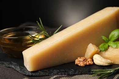 Delicious parmesan cheese, honey, walnuts and basil on grey tablecloth, closeup