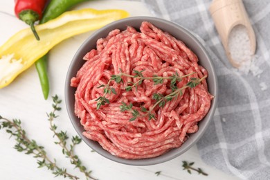 Flat lay composition with fresh raw ground meat and thyme in bowl on white table