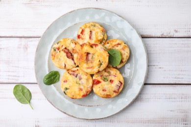 Delicious egg muffins with cheese and bacon on white wooden table, top view