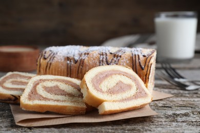 Photo of Tasty cake roll with cream on wooden table, closeup