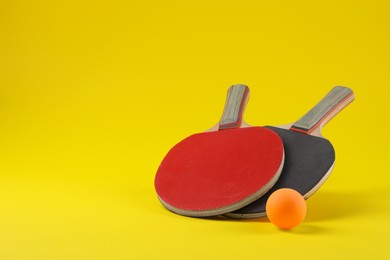 Ping pong ball and rackets on yellow background. Space for text