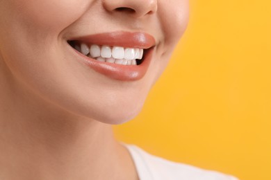 Photo of Woman with clean teeth smiling on yellow background, closeup. Space for text
