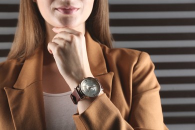 Photo of Woman wearing luxury wristwatch on dark grey background, closeup