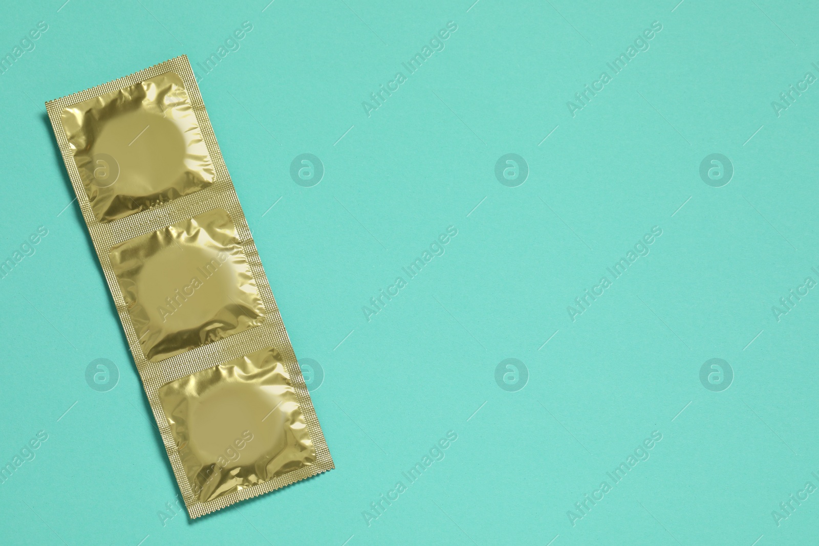 Photo of Condom packages on turquoise background, flat lay and space for text. Safe sex