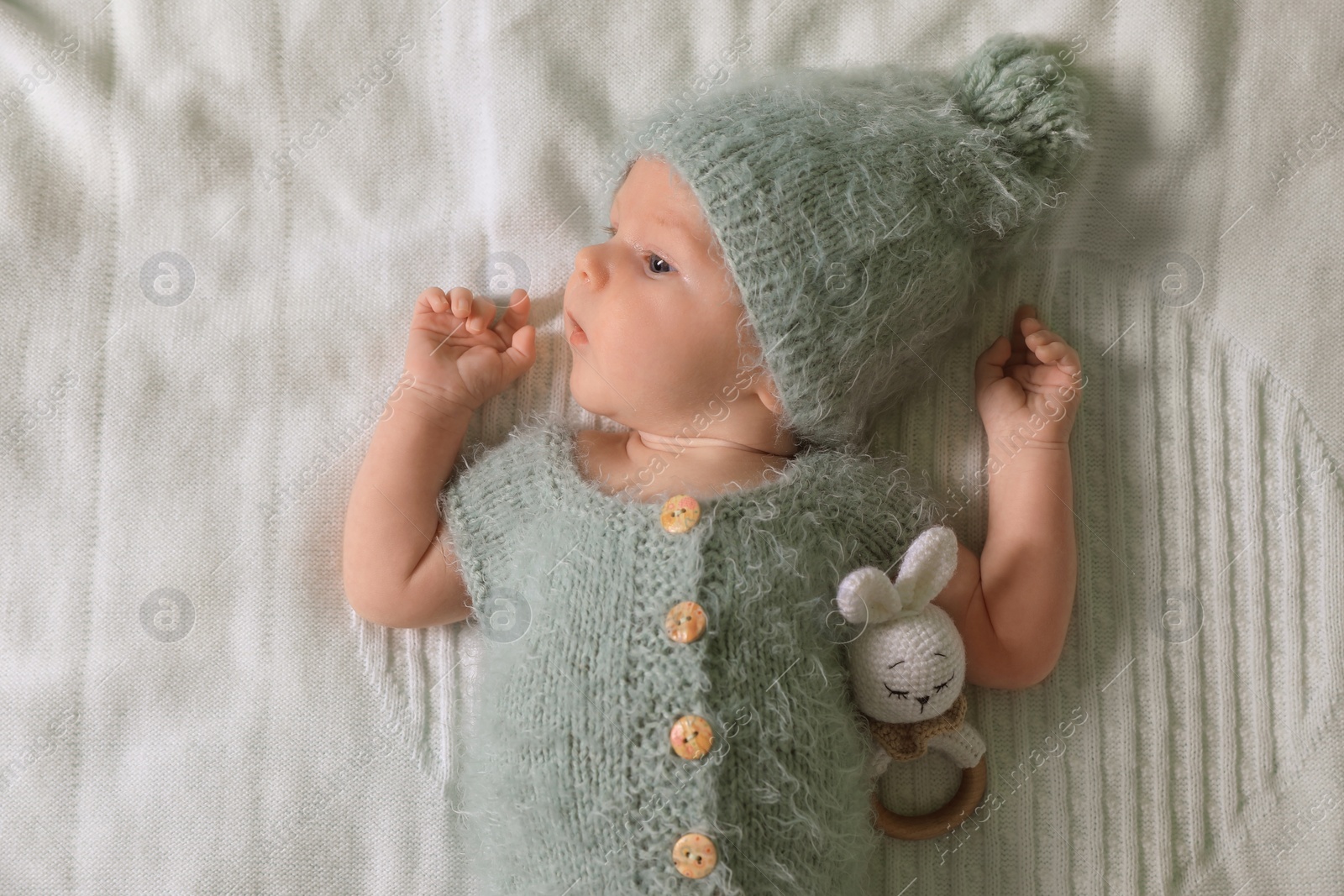 Photo of Cute newborn baby with teething toy on white blanket, top view