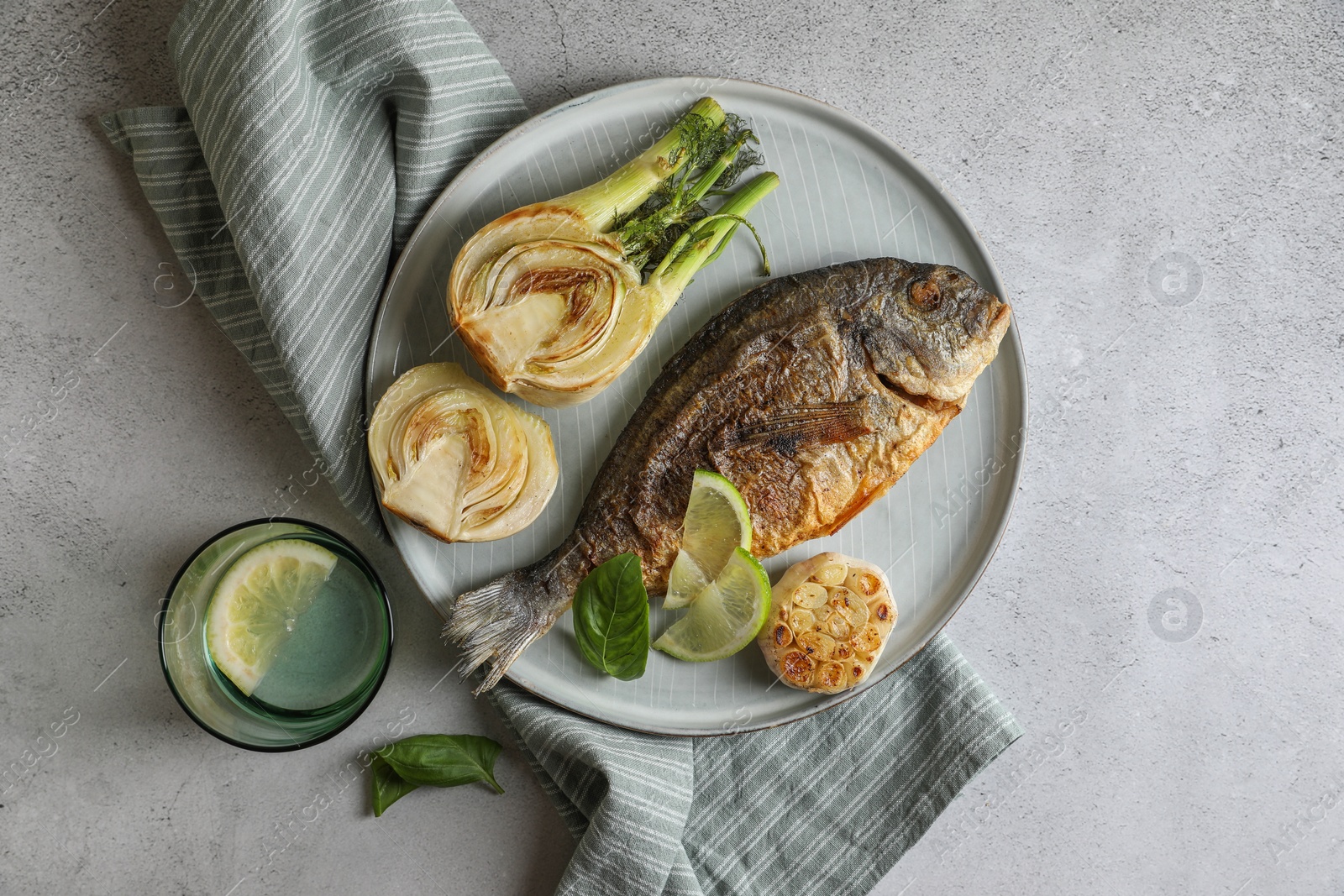 Photo of Delicious dorado fish with vegetables served on light grey table, flat lay