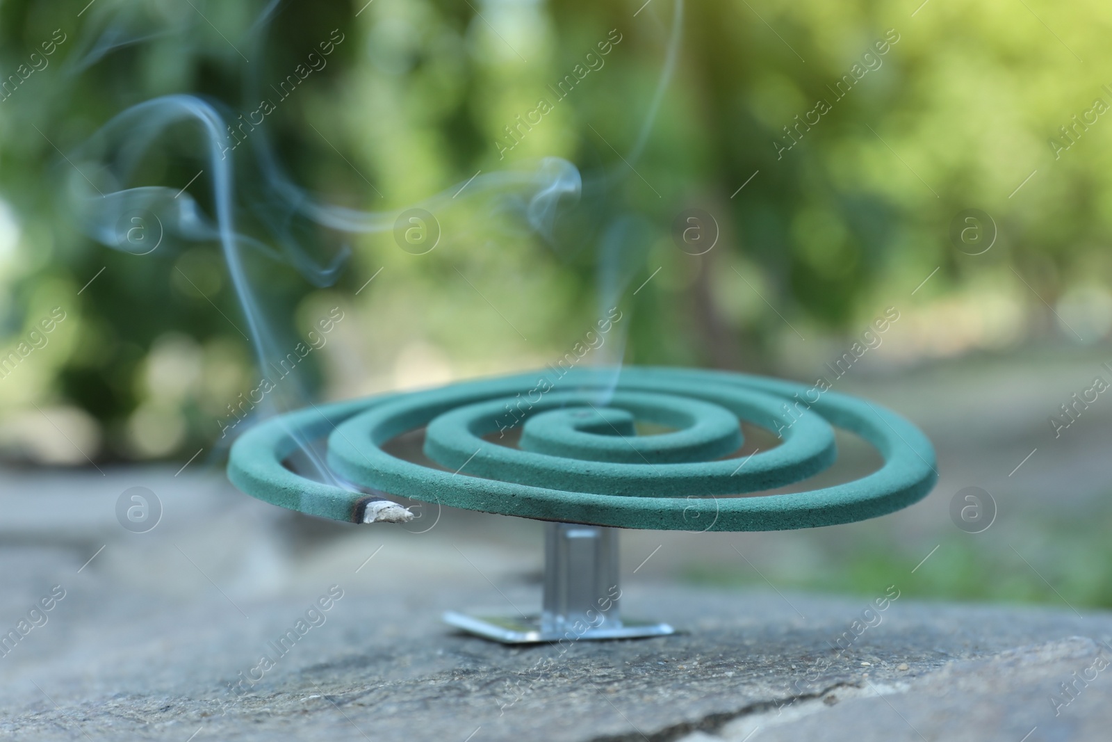 Photo of Smouldering insect repellent coil on stone outdoors