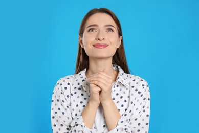 Photo of Woman with clasped hands praying on turquoise background