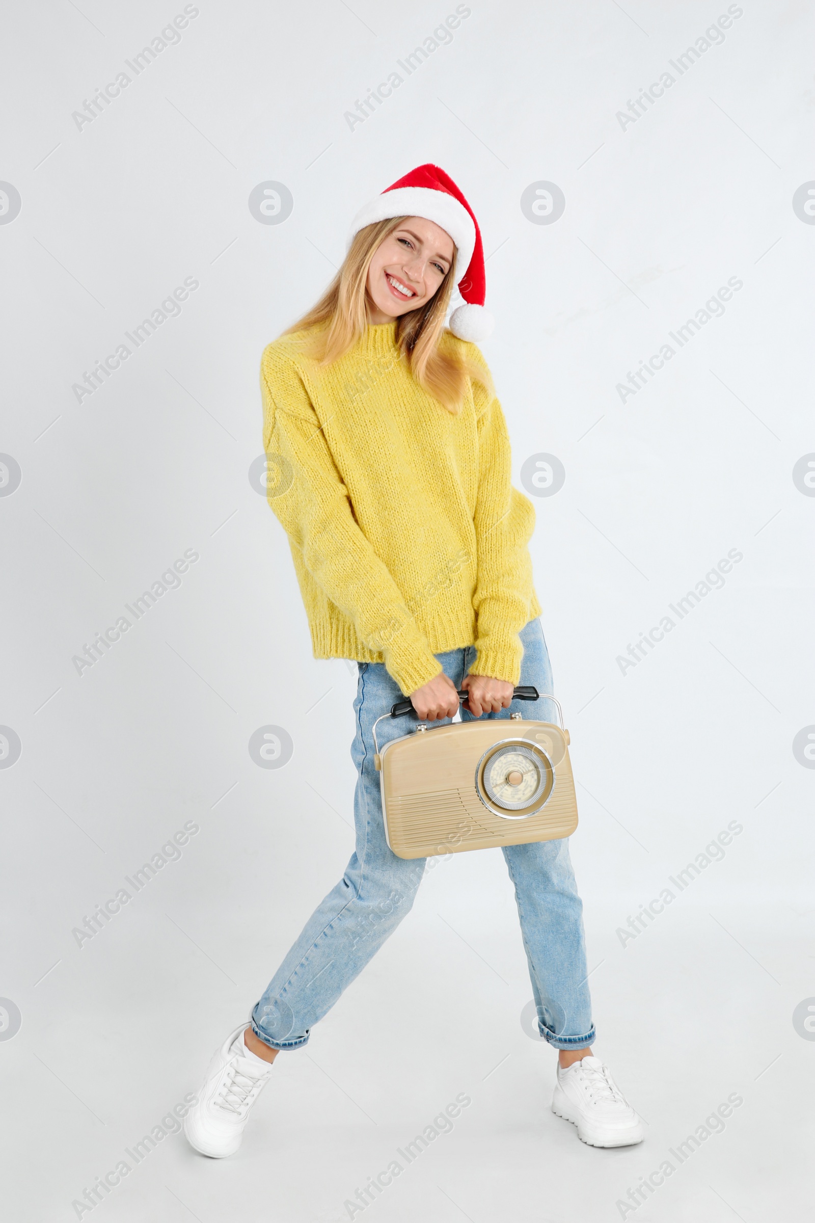 Photo of Happy woman with vintage radio on light grey background. Christmas music