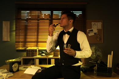 Old fashioned detective with drink and smoking pipe in office