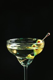 Photo of Martini cocktail with olives on dark background, closeup. Space for text