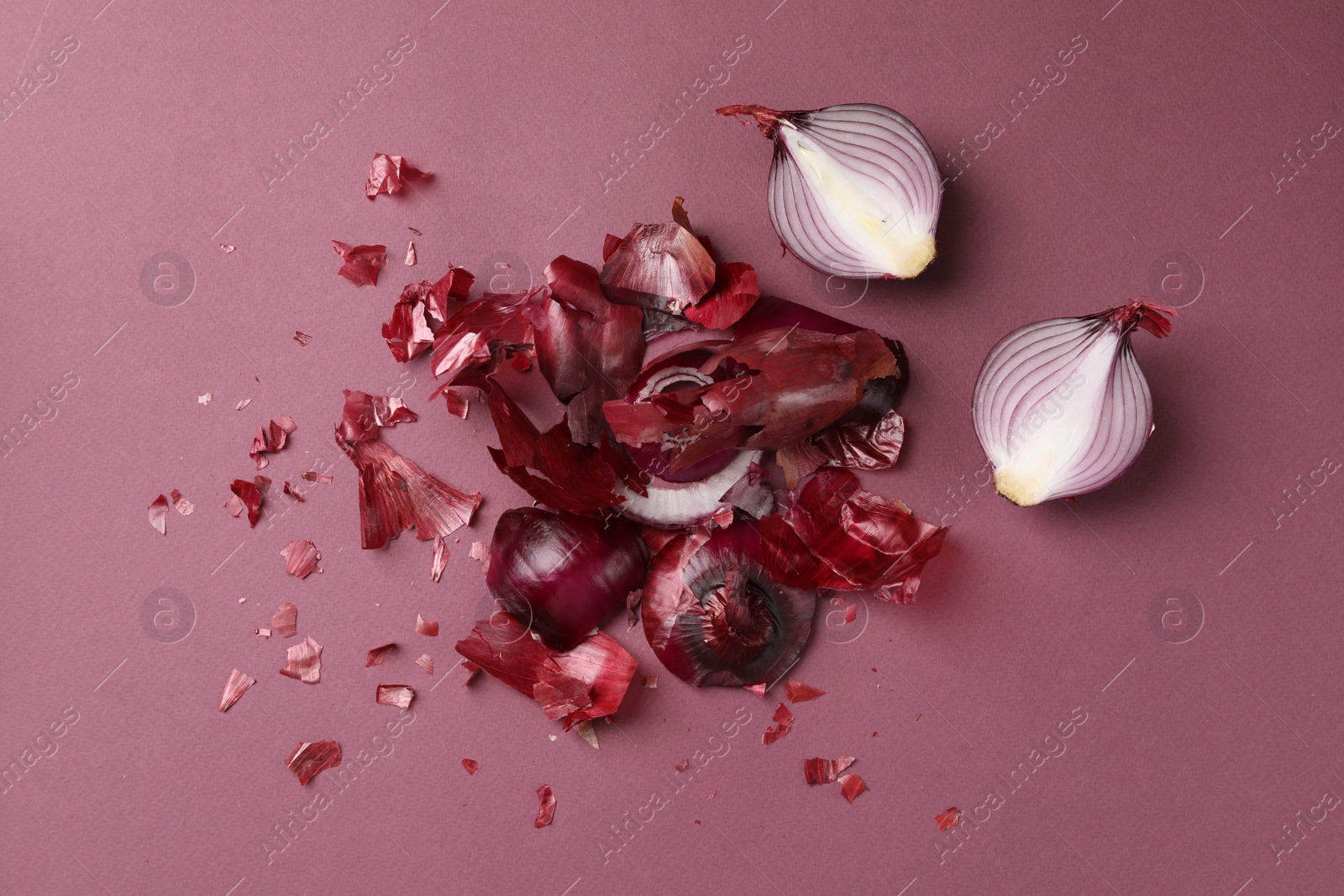 Photo of Cut red onions and peels on dark pink background