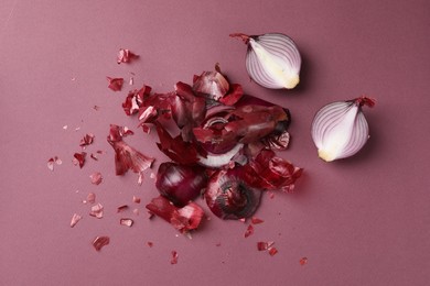 Photo of Cut red onions and peels on dark pink background