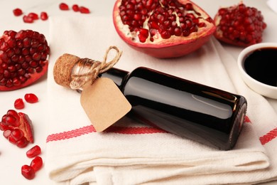 Photo of Glass bottle of pomegranate sauce and fresh ripe fruit on white table