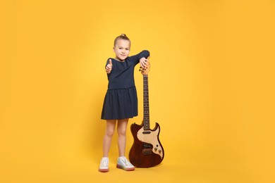 Photo of Happy girl with electric guitar on yellow background