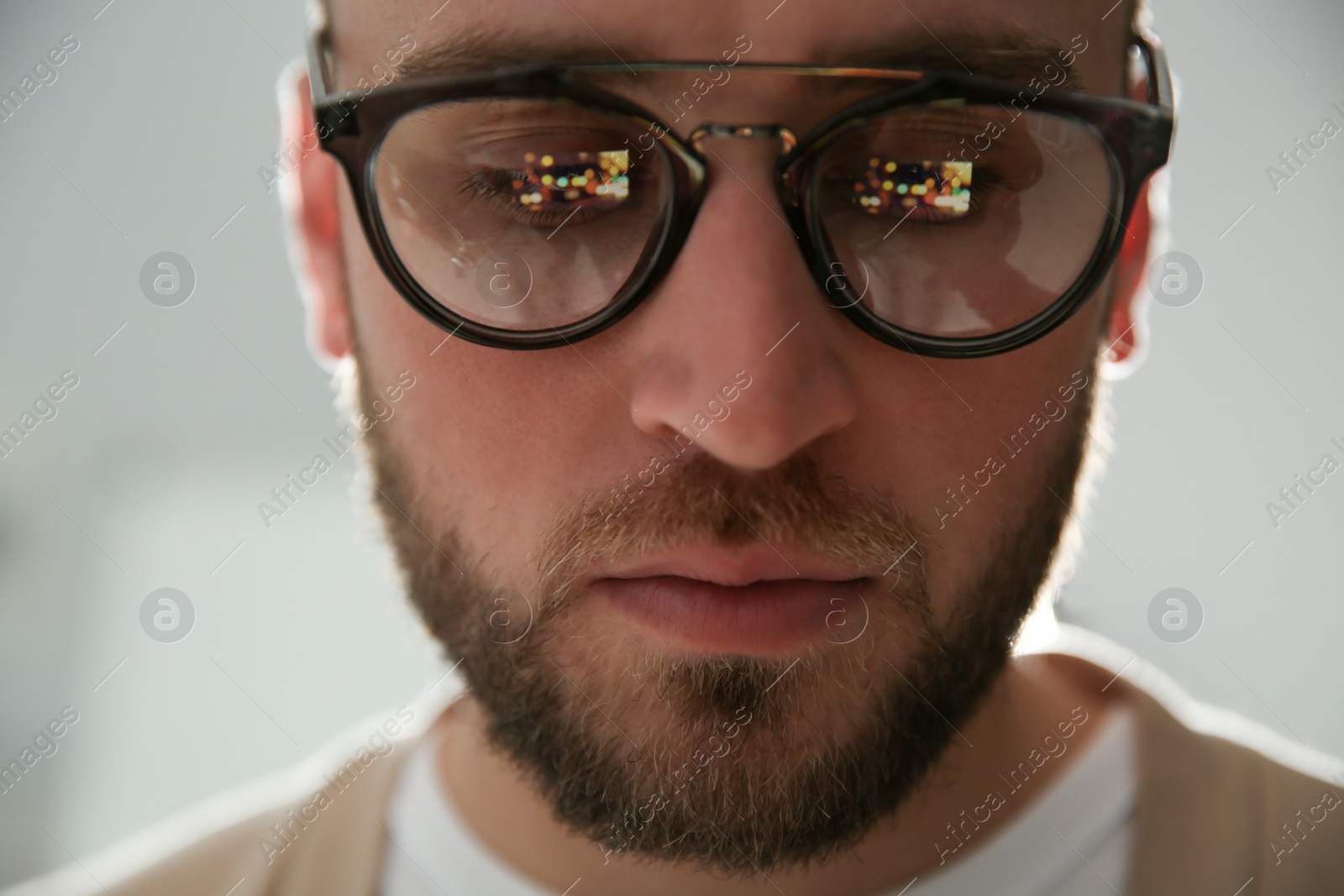 Photo of Young man wearing glasses on blurred background, closeup. Ophthalmology service