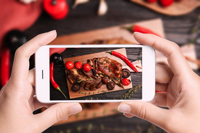 Image of Blogger taking picture of delicious roasted ribs at table, closeup. Food photography