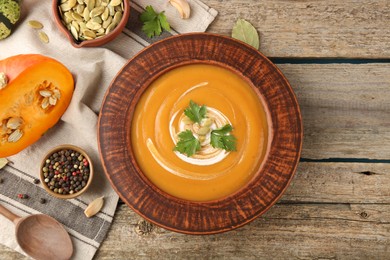 Photo of Delicious pumpkin soup served on wooden table, flat lay