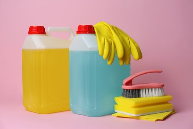 Photo of Canisters of cleaning supplies and tools on pink background