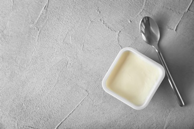 Photo of Plastic cup with tasty yogurt on grey background, top view