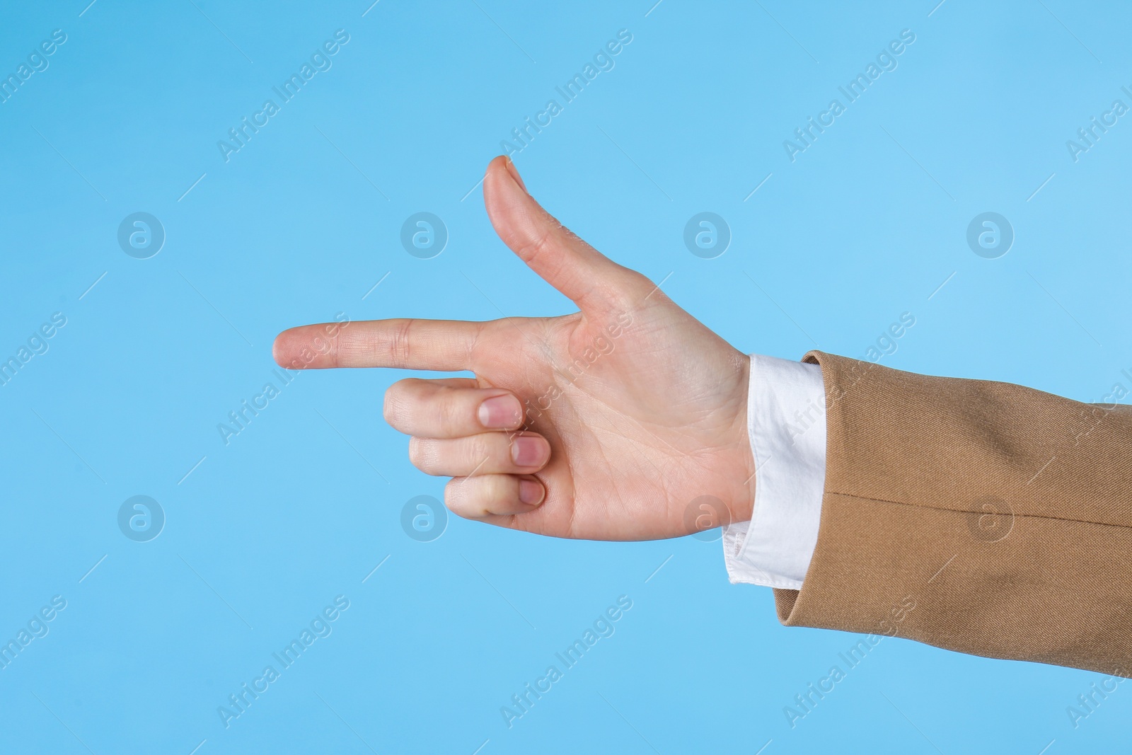 Photo of Businesswoman pointing at something on light blue background, closeup. Finger gesture