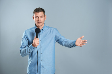 Photo of Male journalist with microphone on grey background