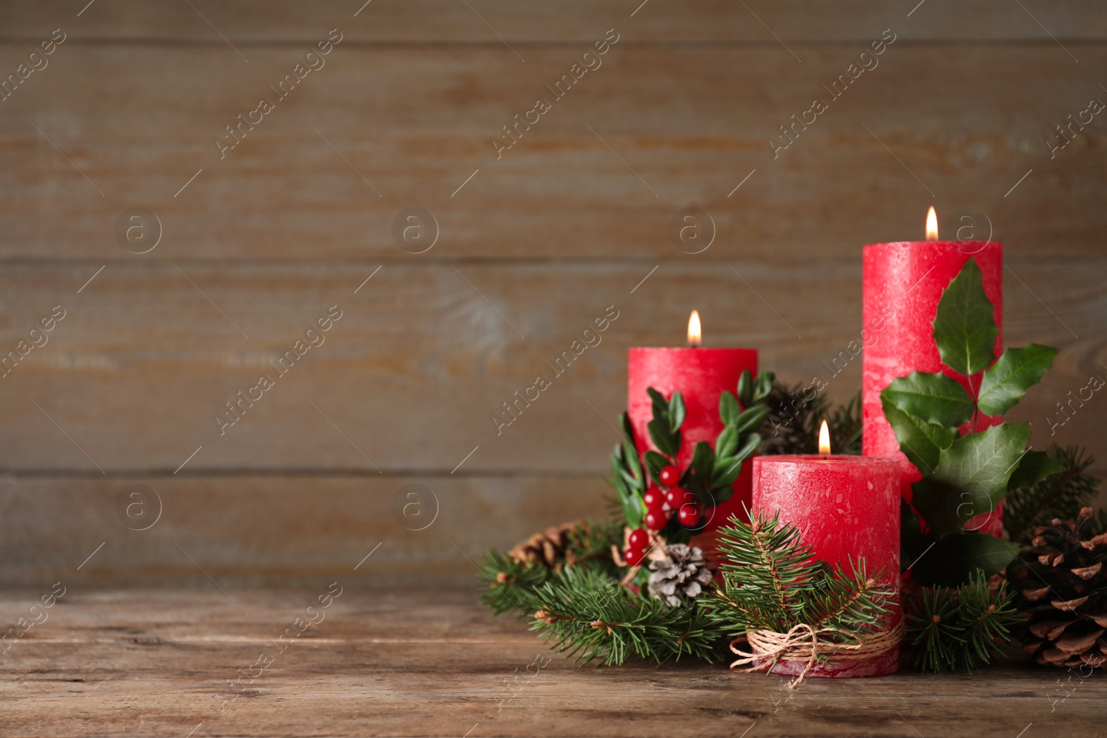 Photo of Burning red candles with Christmas decor on wooden table. Space for text