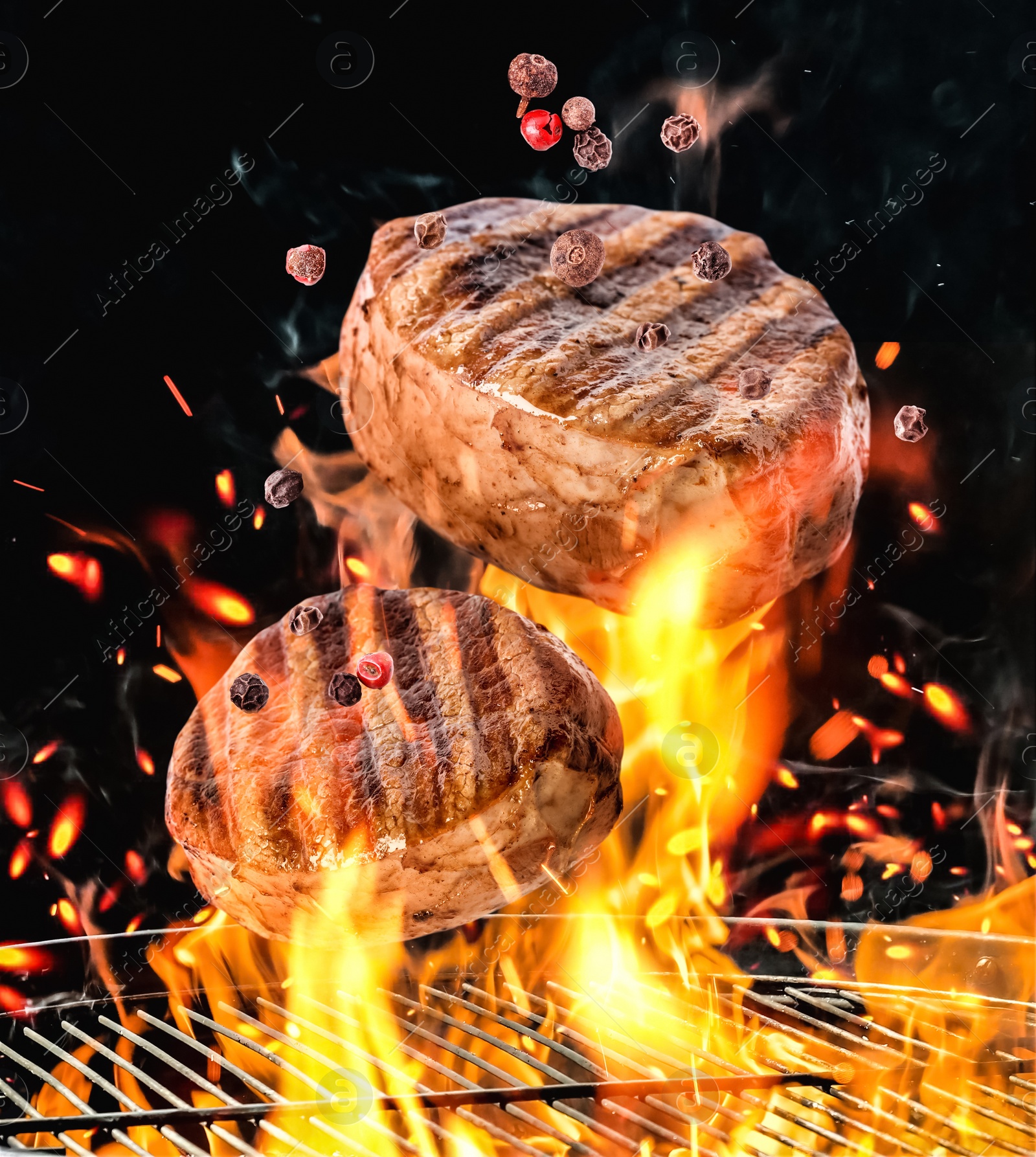 Image of Meat and peppers mix falling onto barbecue grill with flame against black background, closeup