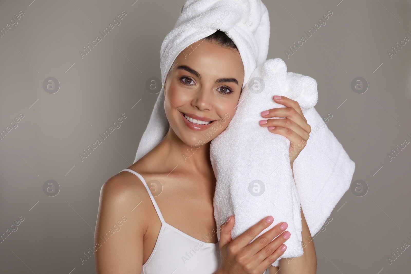 Photo of Beautiful young woman with towels on grey background