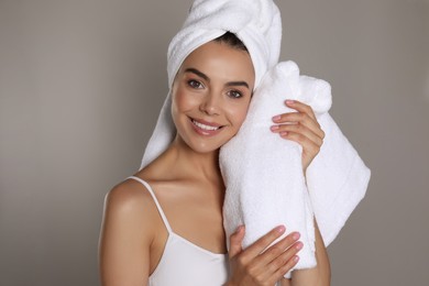 Photo of Beautiful young woman with towels on grey background
