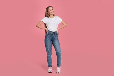 Full length portrait of beautiful teenage girl in casual clothes on pink background