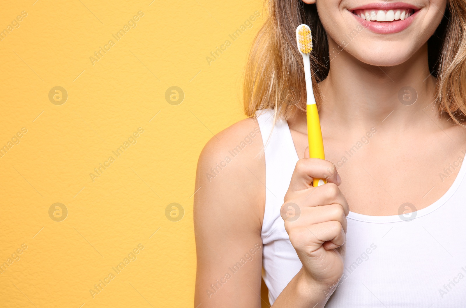 Photo of Young woman with toothbrush on color background, closeup. Space for text