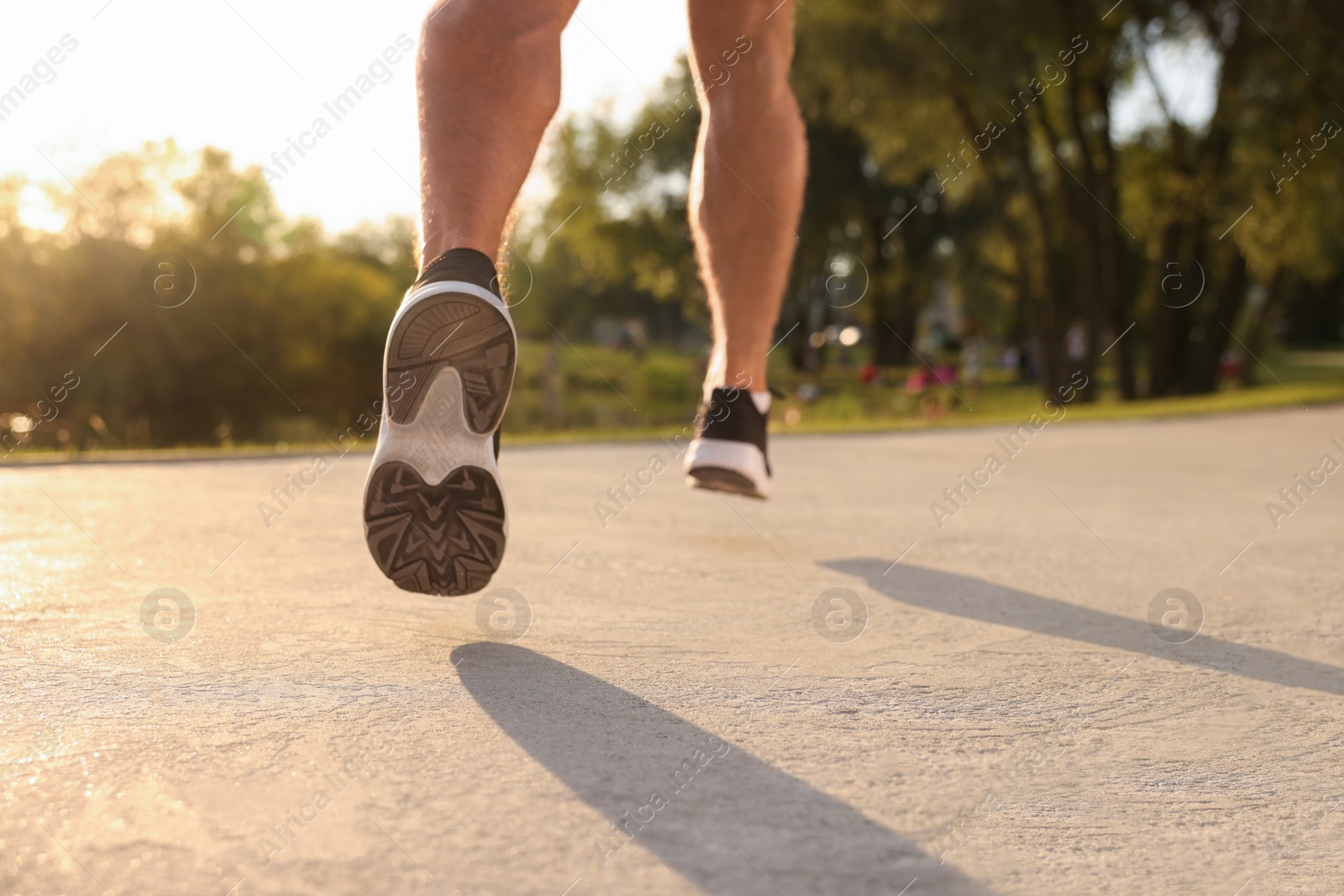 Photo of Man running outdoors in park on sunny day, closeup