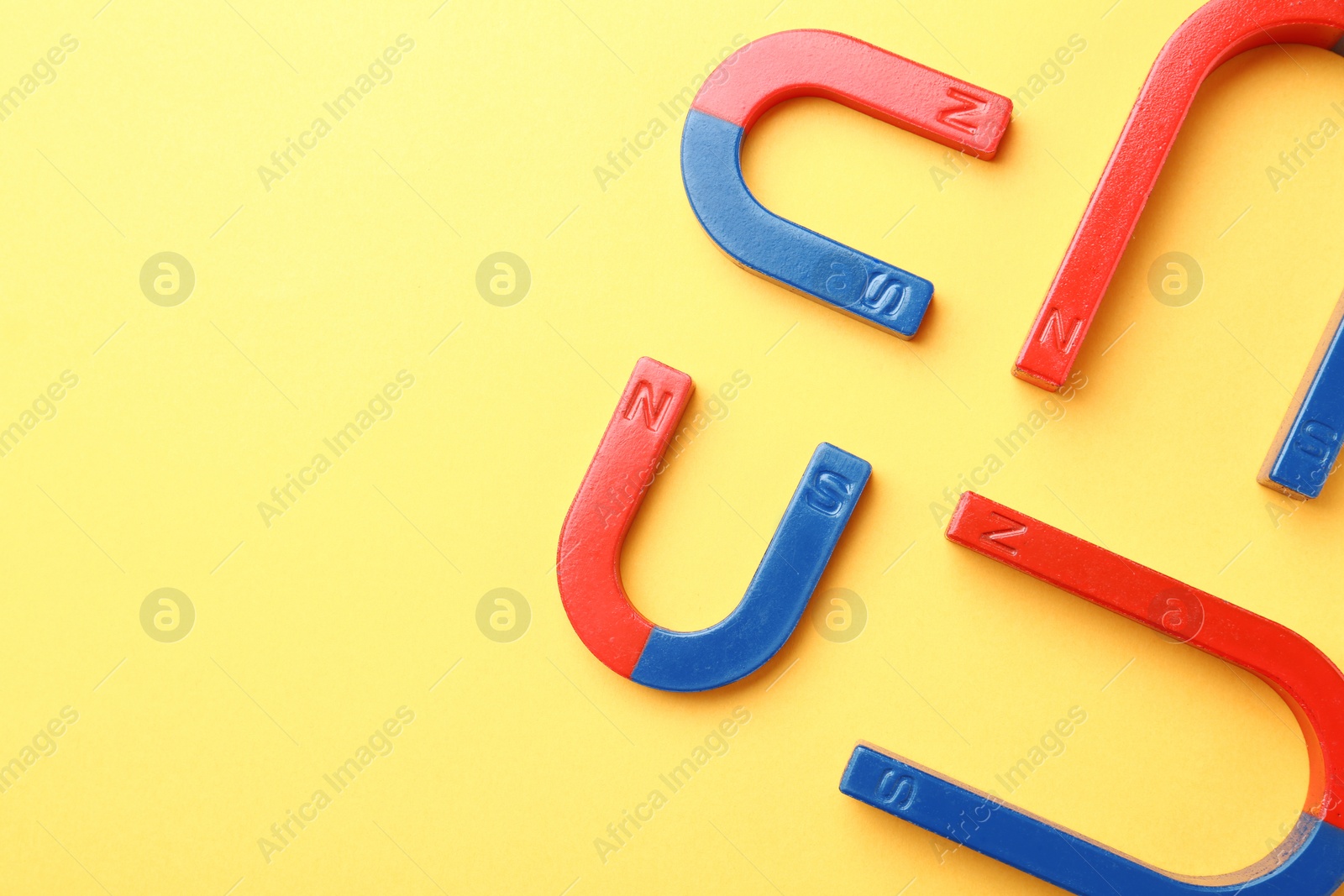 Photo of Red and blue horseshoe magnets on color background, top view with space for text