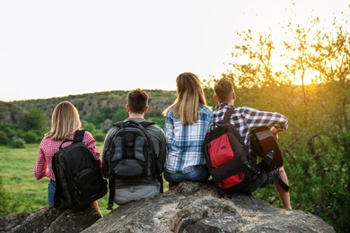 Group of young people with backpacks and guitar in wilderness. Camping season