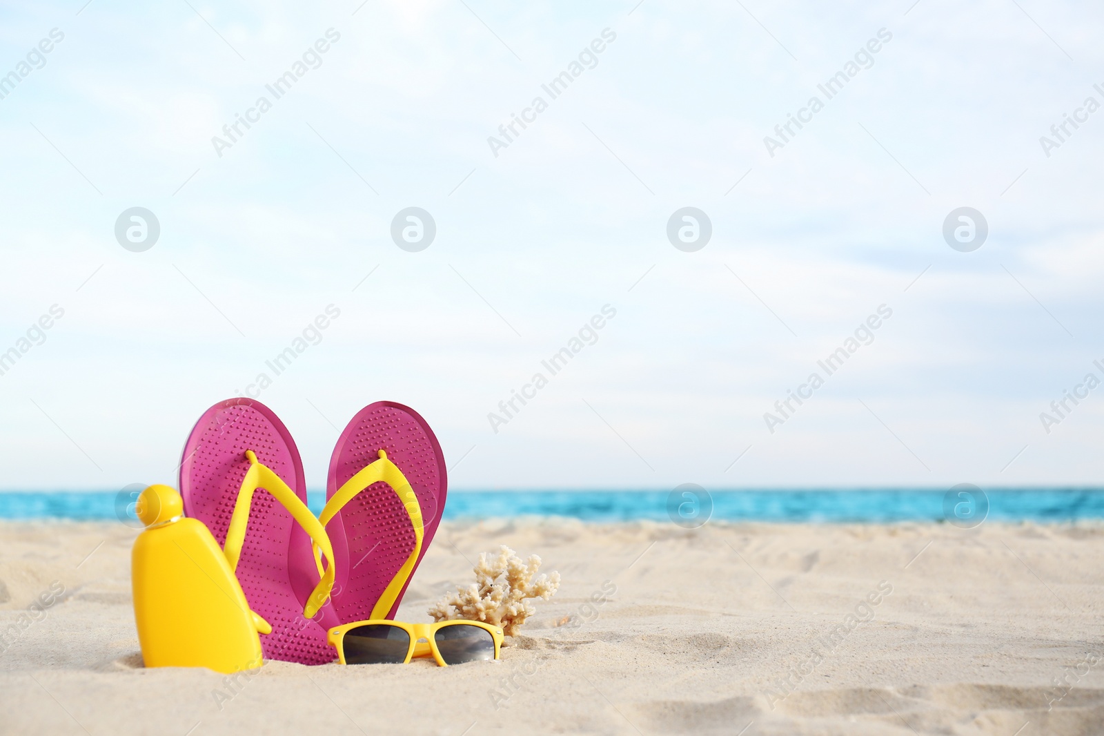 Photo of Different stylish beach objects on sand near sea. Space for text