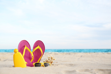 Different stylish beach objects on sand near sea. Space for text